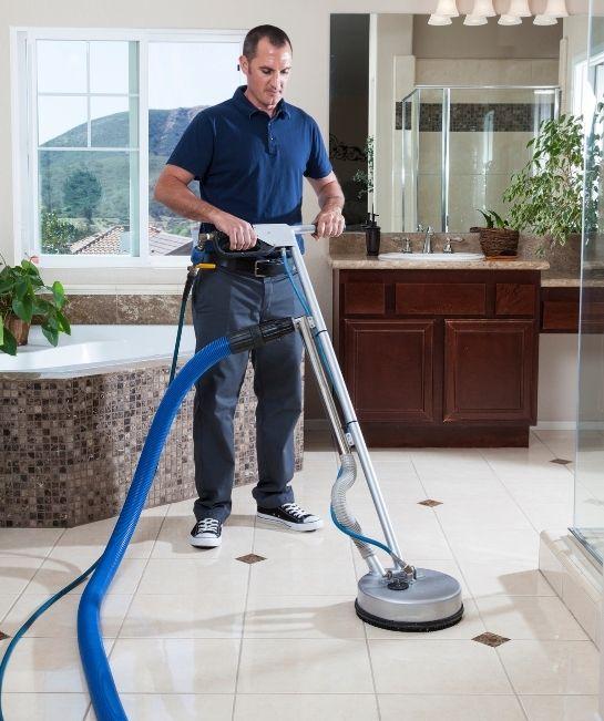 Technician cleaning a tiled floor with a rotary tool